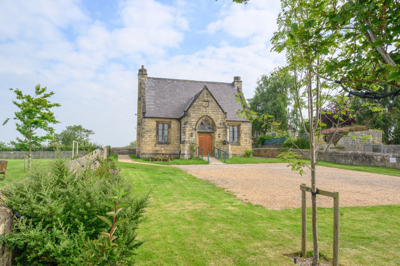 Walton Village Hall — restored stone hall with arched doorway, lawn and parking